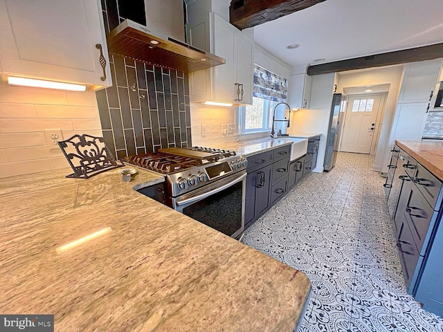 kitchen with appliances with stainless steel finishes, backsplash, a sink, and exhaust hood