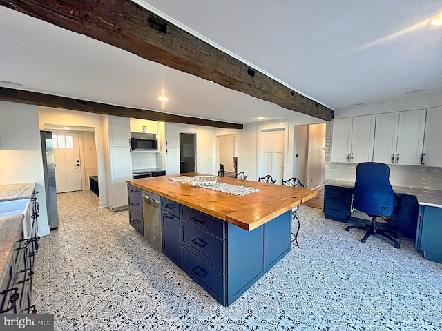 kitchen with blue cabinets, stainless steel microwave, beamed ceiling, and wood counters