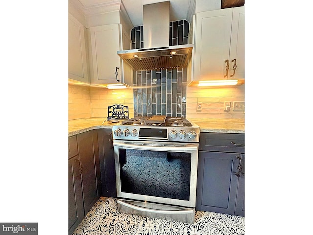 kitchen with white cabinets, wall chimney exhaust hood, tile patterned floors, stainless steel range with gas cooktop, and backsplash