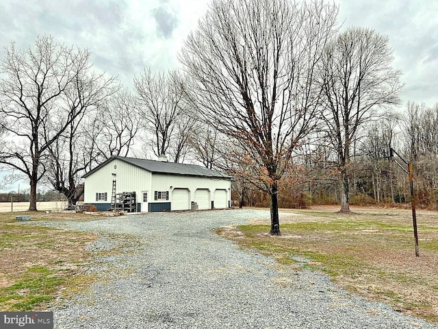 view of side of property with an outdoor structure, driveway, and an attached garage