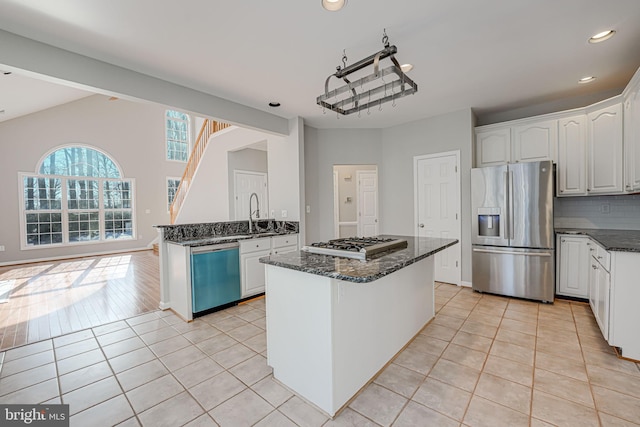 kitchen featuring stainless steel appliances, light tile patterned floors, white cabinets, and dark stone counters