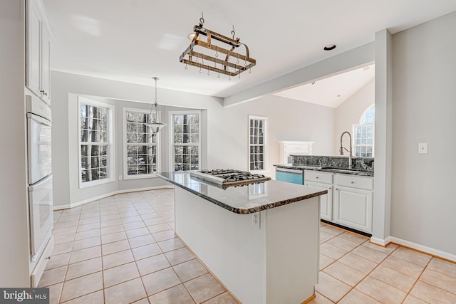 kitchen featuring appliances with stainless steel finishes, white cabinetry, sink, a center island, and light tile patterned floors