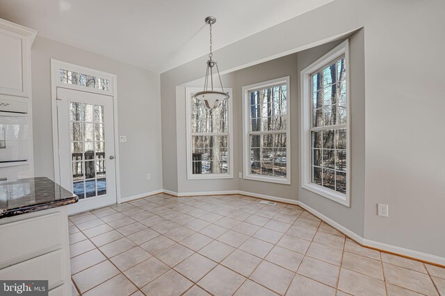 unfurnished dining area featuring lofted ceiling and light tile patterned floors