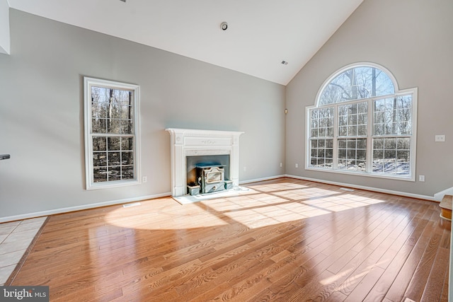 unfurnished living room featuring wood-type flooring and high vaulted ceiling