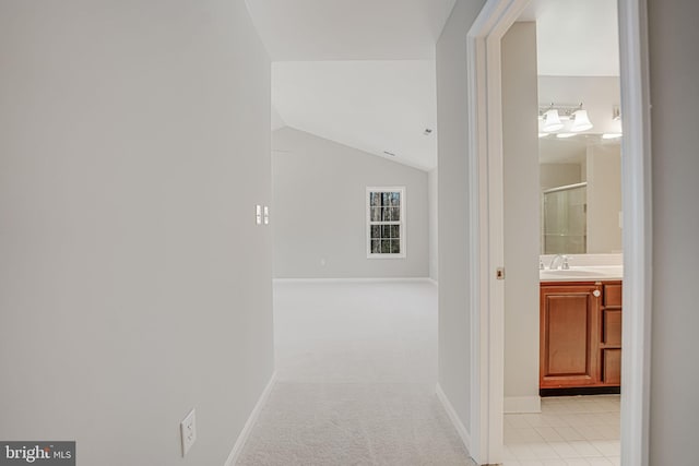 hallway featuring light carpet, sink, and vaulted ceiling