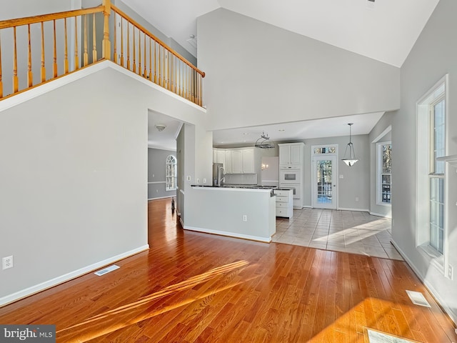 unfurnished living room with high vaulted ceiling and light wood-type flooring