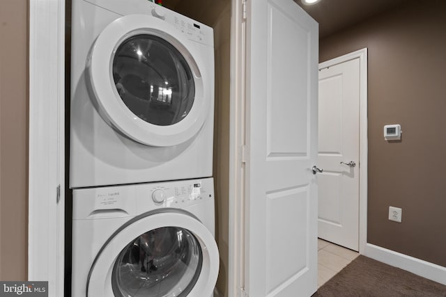 clothes washing area with stacked washer / drying machine and light tile patterned floors