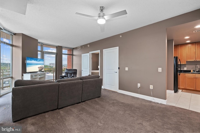 carpeted living room featuring ceiling fan, sink, and a textured ceiling