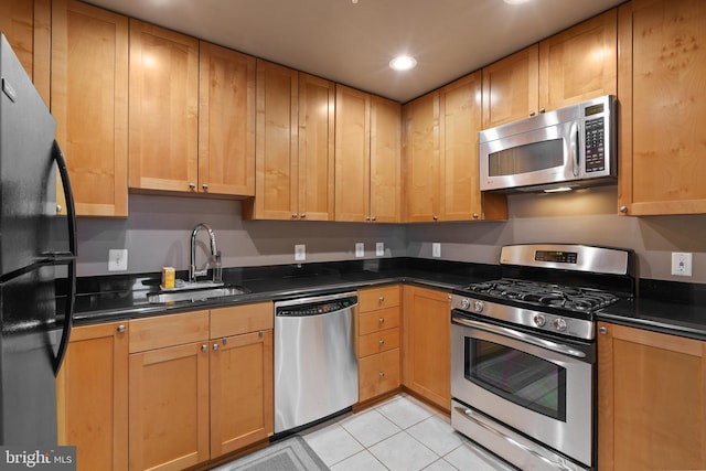 kitchen featuring dark stone countertops, sink, light tile patterned flooring, and appliances with stainless steel finishes