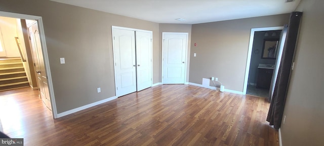 unfurnished bedroom featuring dark hardwood / wood-style flooring, ensuite bath, and a closet