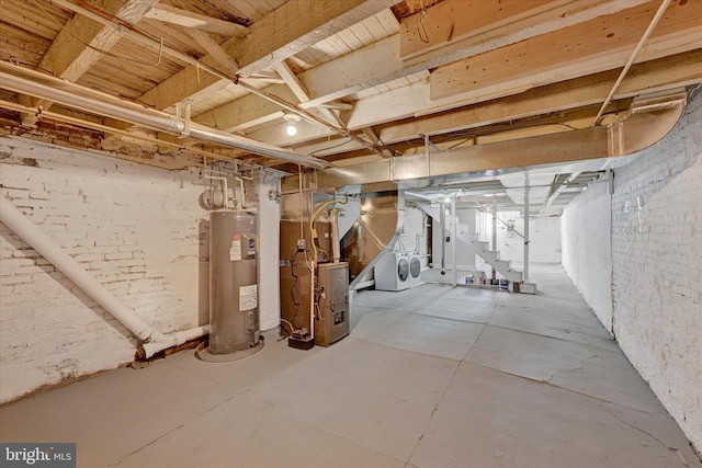 basement with washer and clothes dryer, electric water heater, and heating unit