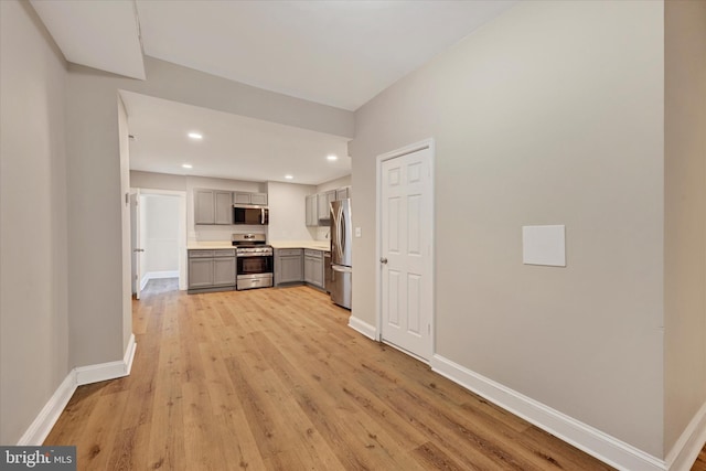 kitchen with appliances with stainless steel finishes, light hardwood / wood-style floors, and gray cabinetry