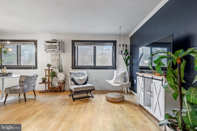 sitting room featuring ornamental molding, an AC wall unit, and light wood-type flooring