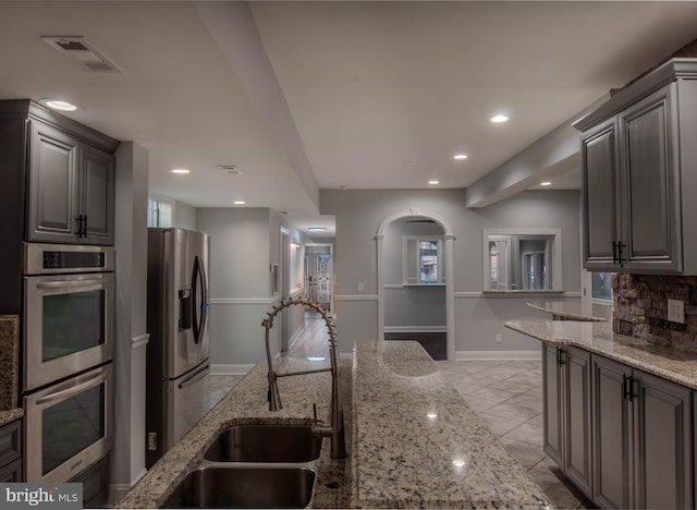 kitchen featuring tasteful backsplash, stainless steel appliances, sink, and light stone counters