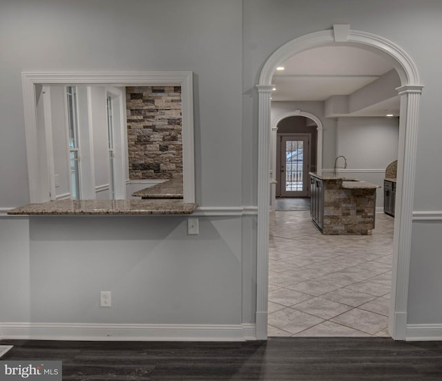 kitchen with light stone counters, sink, and ornate columns