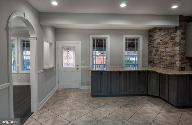 kitchen with light stone counters, decorative columns, and light tile patterned floors