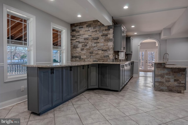 kitchen featuring plenty of natural light, light stone counters, and kitchen peninsula