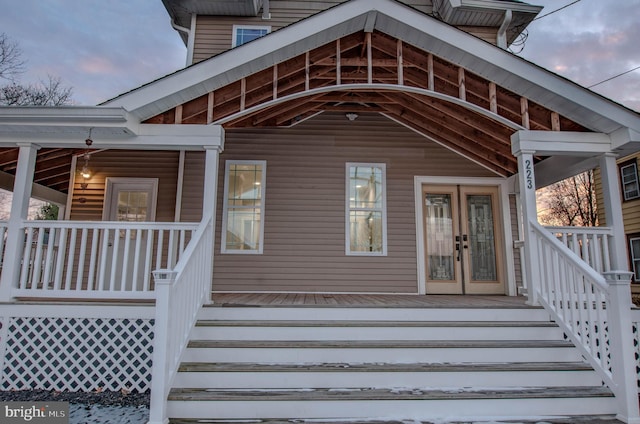 exterior entry at dusk featuring french doors and covered porch