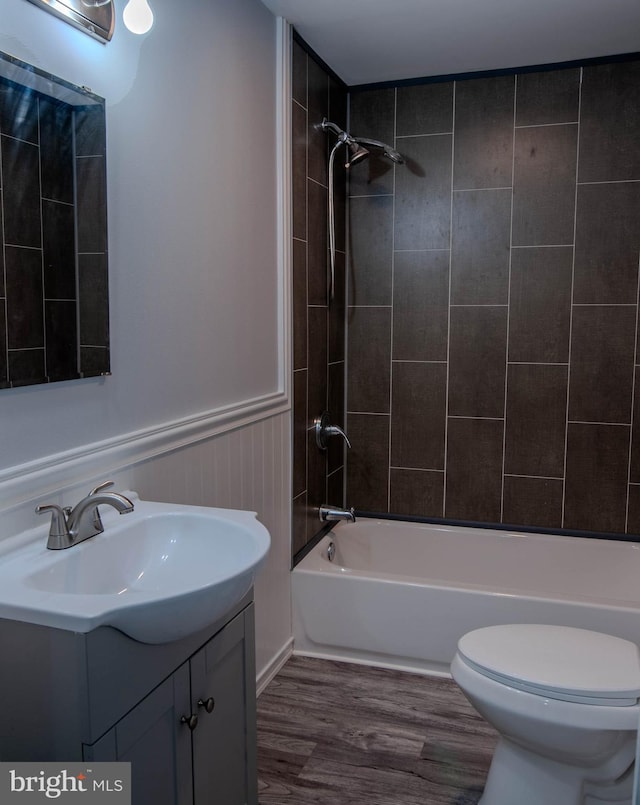 full bathroom featuring tiled shower / bath combo, vanity, hardwood / wood-style flooring, and toilet