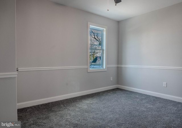 spare room with ceiling fan and dark colored carpet