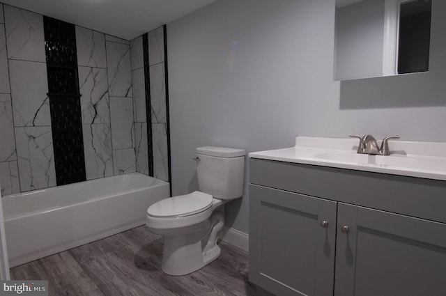 full bathroom featuring vanity, hardwood / wood-style flooring, tiled shower / bath combo, and toilet