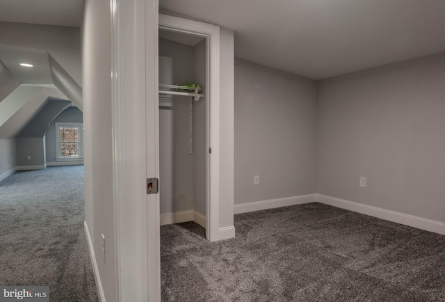 unfurnished bedroom featuring vaulted ceiling, a closet, and carpet flooring