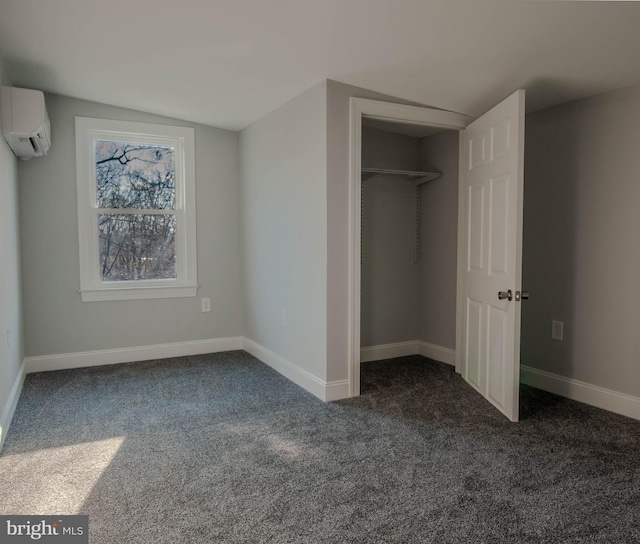 unfurnished bedroom with a wall mounted air conditioner, a closet, and dark colored carpet