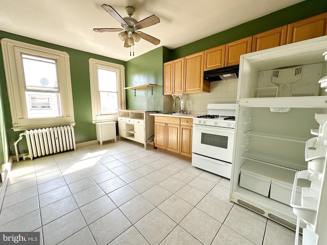 kitchen featuring sink, radiator heating unit, ceiling fan, white gas range oven, and decorative backsplash