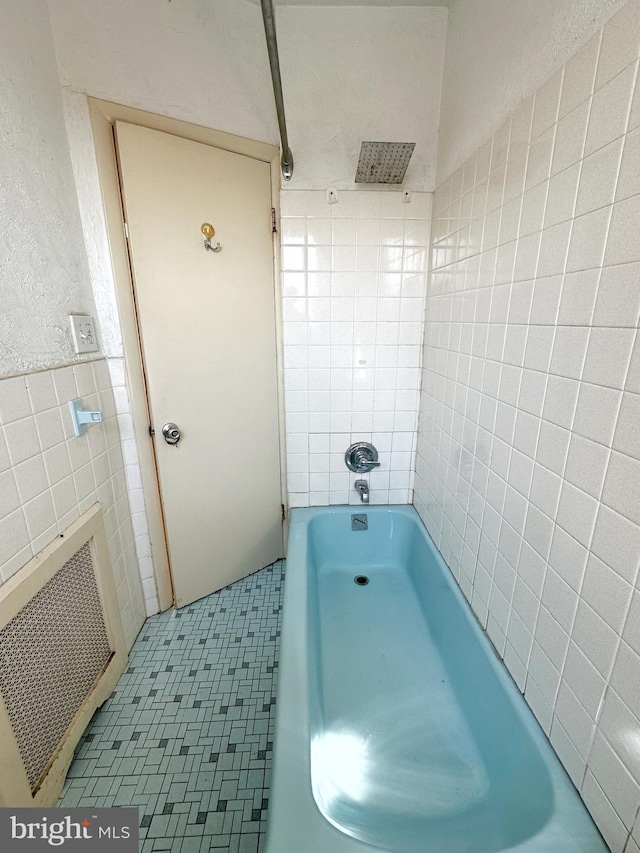 bathroom with shower / tub combination, tile patterned floors, and tile walls