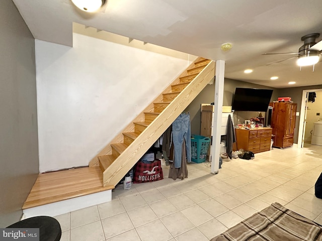 stairway featuring ceiling fan, tile patterned floors, and washer / dryer