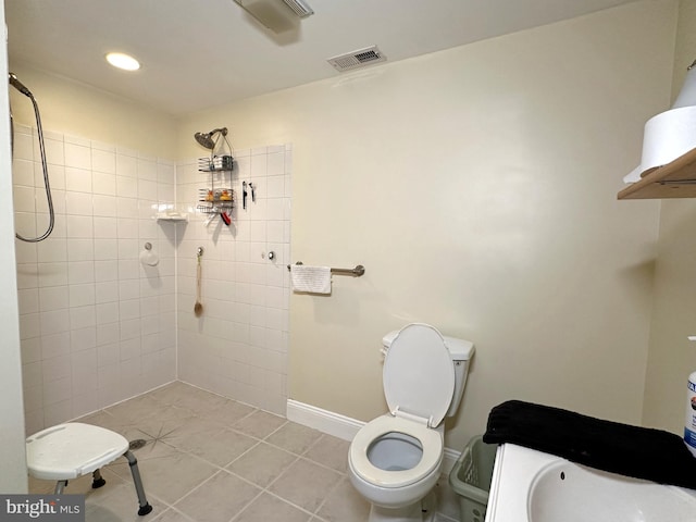 bathroom featuring toilet, tile patterned flooring, and a tile shower