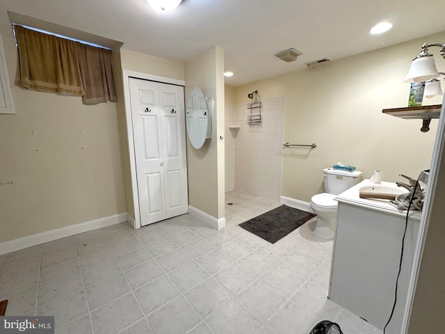 bathroom with vanity, a tile shower, tile patterned floors, and toilet