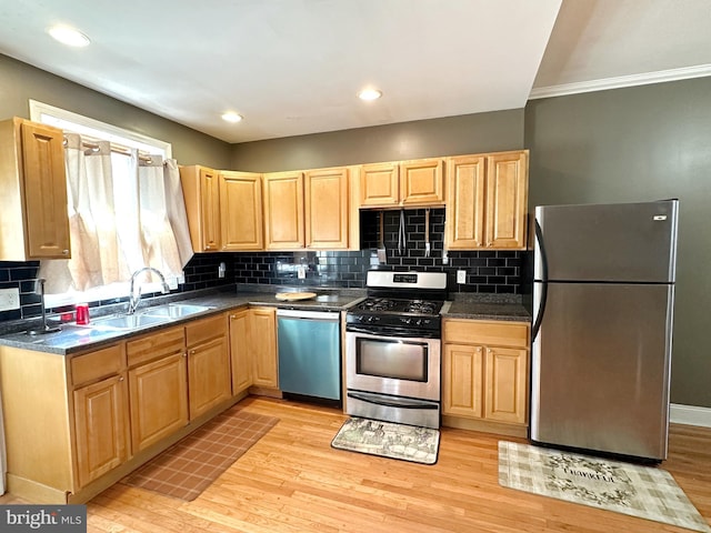 kitchen with stainless steel appliances, sink, light brown cabinetry, and light hardwood / wood-style flooring