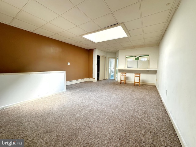 unfurnished room with a baseboard heating unit, carpet floors, and a paneled ceiling