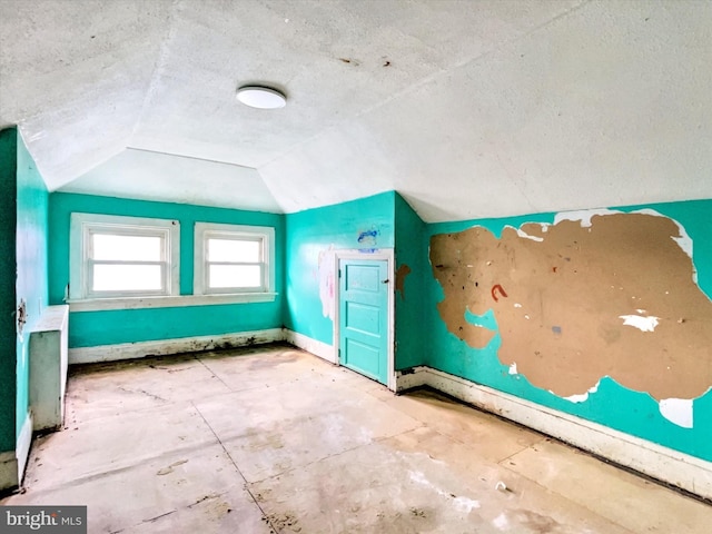 bonus room featuring vaulted ceiling, a textured ceiling, and baseboards