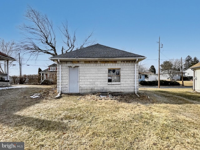 view of side of home with a lawn and roof with shingles