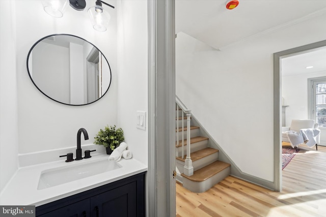 bathroom featuring hardwood / wood-style flooring, ornamental molding, and vanity