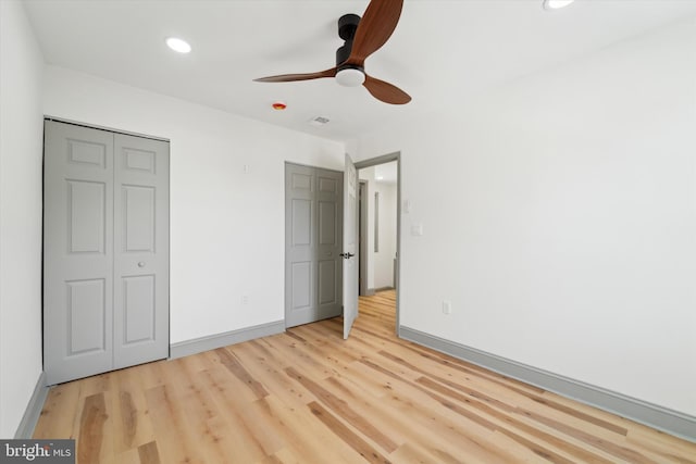 unfurnished bedroom with ceiling fan, a closet, and light wood-type flooring