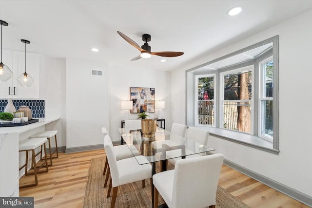 dining space with ceiling fan and light wood-type flooring