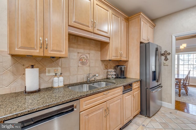 kitchen with backsplash, appliances with stainless steel finishes, sink, and stone counters