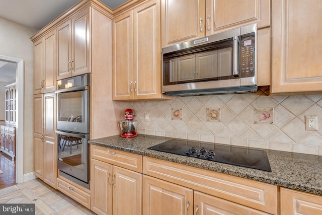 kitchen with light tile patterned flooring, light brown cabinetry, appliances with stainless steel finishes, dark stone counters, and decorative backsplash