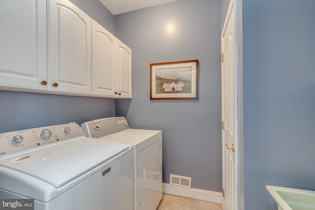 laundry area featuring cabinets, separate washer and dryer, and light tile patterned floors