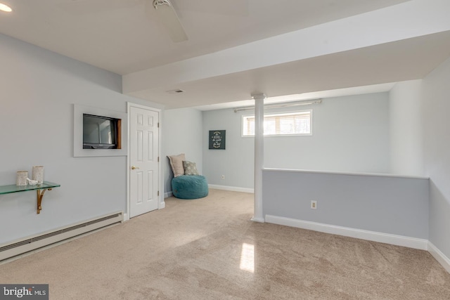 basement with a baseboard heating unit, light carpet, and ceiling fan