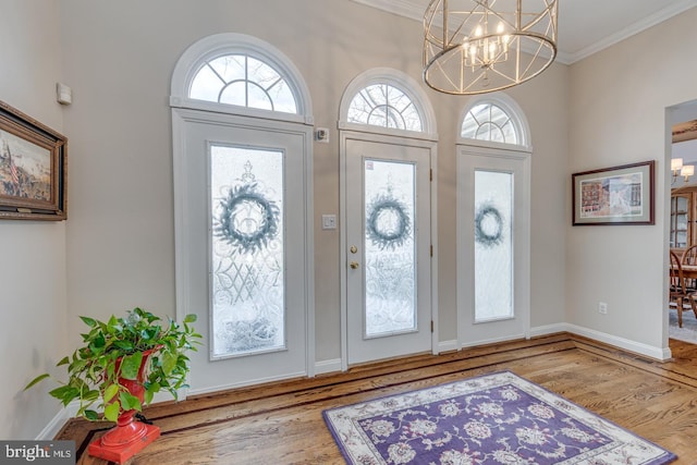 entrance foyer featuring crown molding, hardwood / wood-style floors, and an inviting chandelier