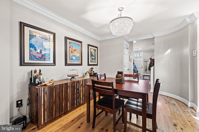 dining room with an inviting chandelier, crown molding, and light hardwood / wood-style flooring