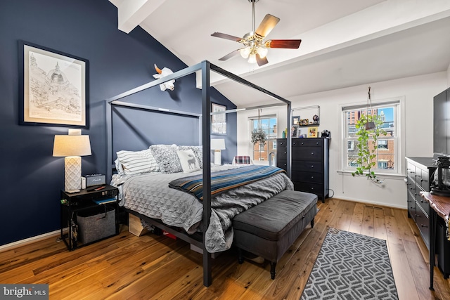 bedroom with lofted ceiling with beams, ceiling fan, hardwood / wood-style floors, and multiple windows