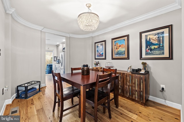 dining room featuring ornamental molding, a notable chandelier, and light wood-type flooring