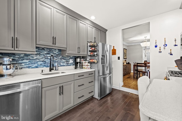 kitchen featuring appliances with stainless steel finishes, dark hardwood / wood-style floors, sink, gray cabinetry, and backsplash