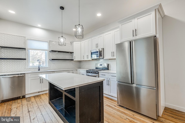 kitchen featuring a kitchen island, tasteful backsplash, white cabinetry, hanging light fixtures, and stainless steel appliances