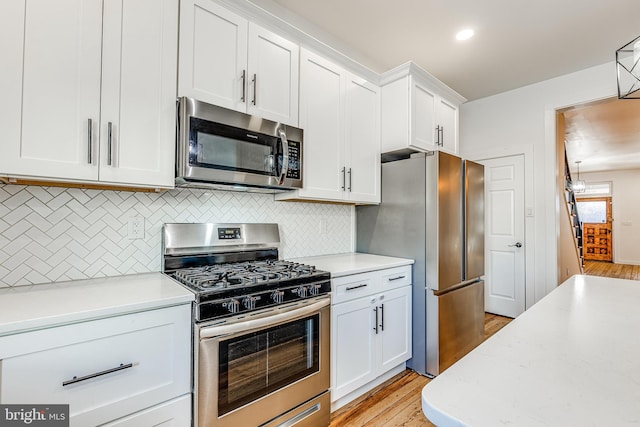 kitchen with stainless steel appliances, white cabinetry, backsplash, and light hardwood / wood-style floors